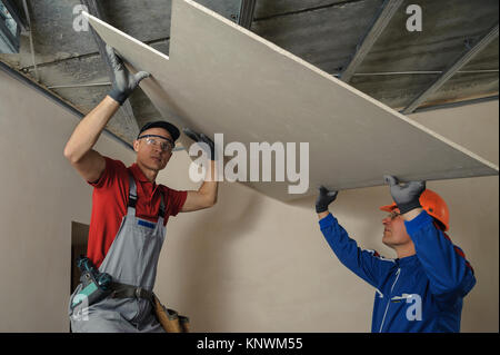 Drywall Installers. Men holding a gypsum board figured cut Stockfoto