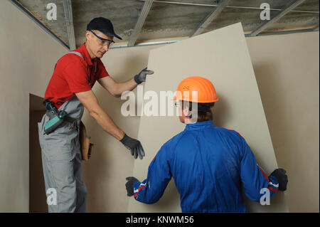 Drywall Installers. Men holding a gypsum board figured cut Stockfoto