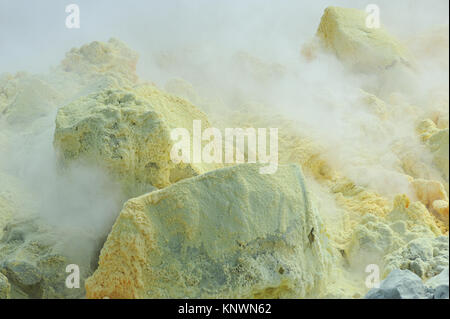 Wolken von Schwefelsäure beladen Dampf Bülow aus dem aktiven Fumarolen und Kaution Schwefel auf Lavagestein innerhalb der Caldera des Sierra Negra Vulkans. Ist Stockfoto