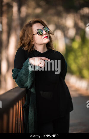 Frau mit Sonnenbrille Possing im Park Stockfoto