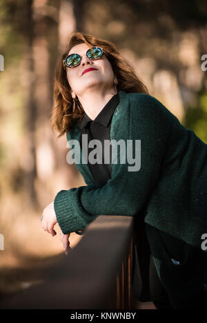 Frau mit Sonnenbrille Possing im Park Stockfoto