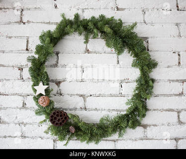 Detailansicht der Runde elegante Weihnachten Kranz an den weißen Wand. Kranz mit Ratten Kugeln dekoriert, getrocknete Blumen von Lotus und Holz- Stern Stockfoto