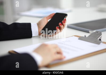 Unternehmerin über Ihr Telefon im Büro auf dem Schreibtisch Stockfoto