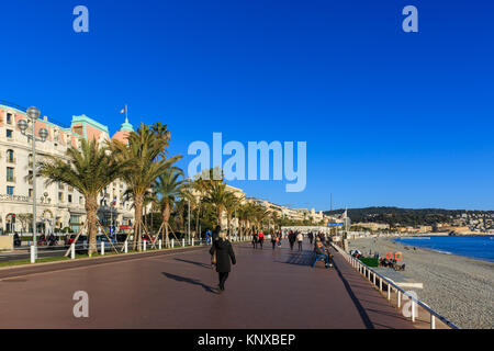 Menschen zu Fuß im Sonnenschein auf der Strandpromenade parallel zur Promenade des Anglais, Nizza, Côte d'Azur, Frankreich Stockfoto