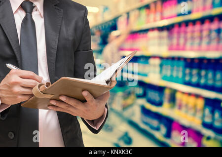 Geschäftsmann Schreiben der Hinweis Buch über Supermarkt blur Hintergrund, Business Konzept Stockfoto