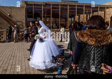 Eine junge USBEKISCHE Paar zu Fuß durch die Straßen von Chiwa nach der Hochzeit, Chiwa, Usbekistan Stockfoto
