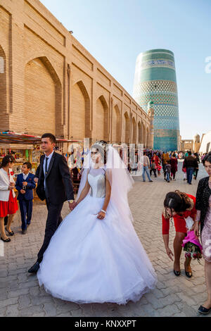 Eine junge USBEKISCHE Paar zu Fuß durch die Straßen von Chiwa nach der Hochzeit, Chiwa, Usbekistan Stockfoto