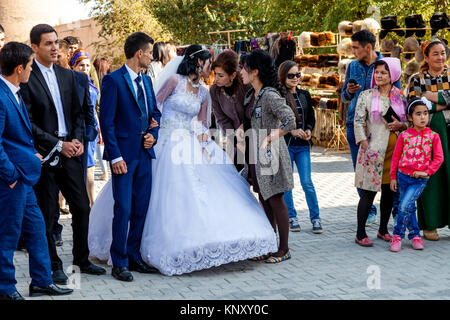 Eine junge USBEKISCHE Paar zu Fuß durch die Straßen von Chiwa nach der Hochzeit, Chiwa, Usbekistan Stockfoto