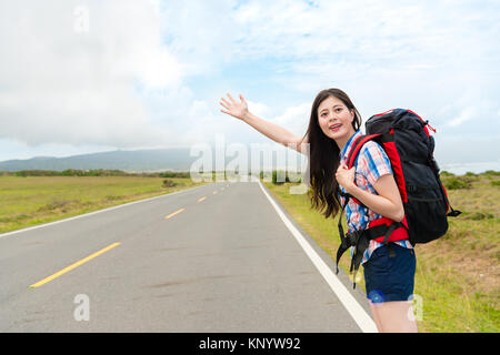 Elegante attraktive Reisenden stehen auf der Straße, per Anhalter Geste Suche vorbeifahrenden Auto wenn Sie wandern in Reisen. Stockfoto