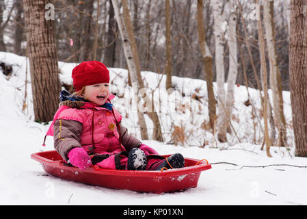 Ein Lachen kleines Mädchen (3 Jahre alt) Rodeln in Quebec Stockfoto