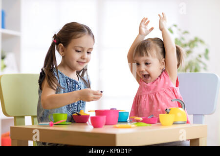 Kinder spielen mit Plastikgeschirr