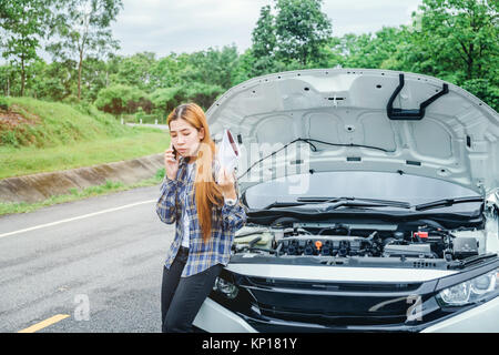 Junge Frau ruft zur Unterstützung mit seinem Auto eine Panne am Straßenrand Stockfoto