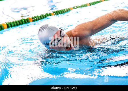 Älterer Mann Schwimmen im Innenpool. Stockfoto