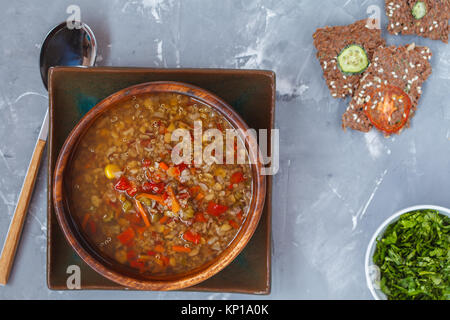 Peruanische Suppe mit Quinoa, roter Reis und Linsen in eine hölzerne Schüssel mit Kräutern und gesundes Knäckebrot. Gesunde vegane Ernährung Konzept. Stockfoto