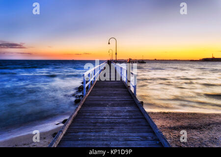 Historischen Fachwerkhäuser langen Steg aus Port Melbourne Beach auf Port Phillip Bay in Melbourne, Australien. Farbenfroher Sonnenuntergang mit Sonne über Sea Horizon refle Stockfoto