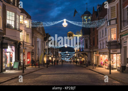 Die Hohe Straße in Guildford mit Weihnachtsbeleuchtung und die berühmten Guildhall gold Uhr in der blauen Stunde auf einem Late night shopping Tag, England Großbritannien Stockfoto