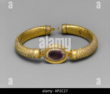 Dieses griechische Armband aus dem 2. Jahrhundert v. Chr. verfügt über ein zentrales Glasmedaillon in einem goldenen Band. Die Band ist mit filigraner und granulierter Kreation dekoriert und zeigt eine komplizierte Handwerkskunst. Stockfoto