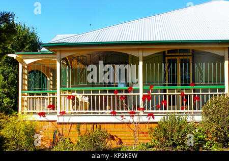 Queensland Haus mit verzierten Metall Bars auf der umlaufenden Veranda, Metalldach und poinsettas tierisch darauf vor Stockfoto