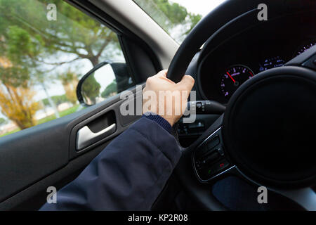 Mann, der das Auto auf der Straße halten Sie das Lenkrad mit einer Hand. Stockfoto