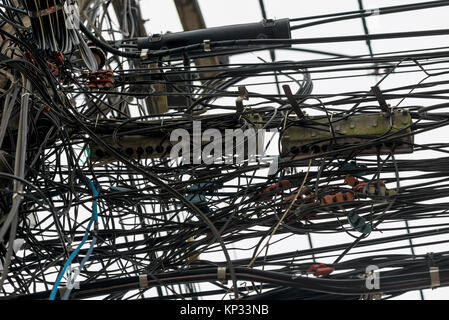 Zufällig hängenden Drähte auf elektrische Pole in Thailand closeup Stockfoto