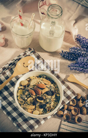 Frühstück eingestellt. mix Hafer Müsli in weiße Schüssel mit rosa Herzen süße Marshmallow auf Tisch Set Background, Dienen mit weißer Milch in Glas und Flasche, oben Stockfoto