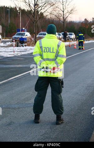 Schönberg, Deutschland. 13 Dez, 2017. Einen Zollbeamten steht am ehemaligen Grenzübergang Deutschland/Tschechien in der Nähe von Schönberg, Deutschland, 13. Dezember 2017. Vor allem die Bekämpfung der Kriminalität im Zusammenhang mit Betäubungsmitteln ist einer der Schwerpunkte in der Zusammenarbeit zwischen den regionalen Polizei Verzeichnis Karlovy Vary (Tschechien) im Rahmen eines gemeinsamen EU-Projekt. Achtung Redaktionen: License Plate pixelised Für Persönlichkeit gründen. Credit: Bodo Schackow/dpa-Zentralbild/dpa/Alamy leben Nachrichten Stockfoto