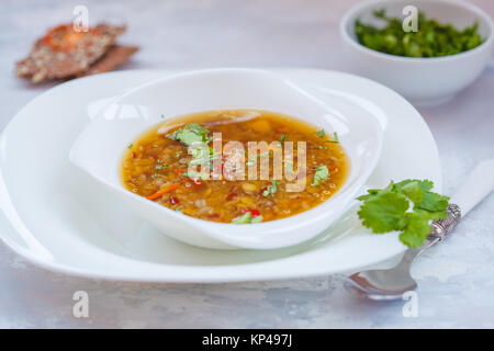 Peruanische quinoa Suppe, roten Reis und Linsen in eine weiße Platte mit Kräutern und Knäckebrot. Gesunde vegane Ernährung Konzept. Stockfoto