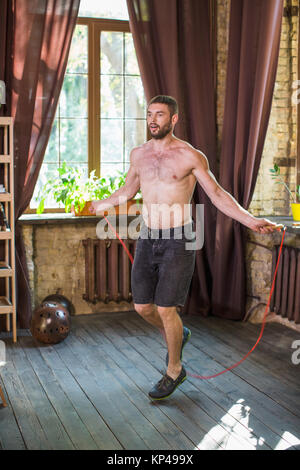 Mann tun Training, Springen mit Seil im Wohnzimmer. Stockfoto