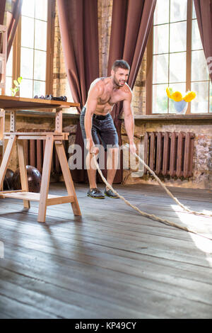 Junger Mann, verschwitzt, Arbeiten mit Schlacht Seile. Stockfoto