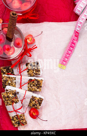 Diät Müsliriegel mit detox Apfel-zimt-Wasser und Maßband auf rote Paprika und Holz- Hintergrund. Ansicht von oben. Flach Stockfoto