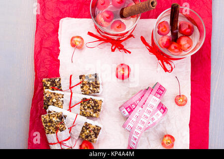 Diät Müsliriegel mit detox Apfel-zimt-Wasser und Maßband auf rote Paprika und Holz- Hintergrund. Ansicht von oben. Flach Stockfoto