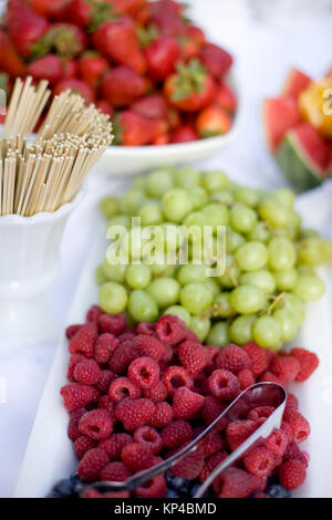 Eine Auswahl an Speisen auf dem Tisch, darunter auch Weintrauben, Himbeeren, Heidelbeeren, Erdbeeren, und Wassermelone Stockfoto