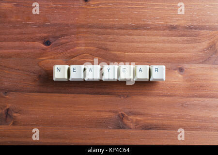 Frohes neues Jahr word mit weißen Computer Tastatur geschrieben Tasten Tasten auf Holz- Hintergrund. Urlaub Technologie Konzept. Stockfoto