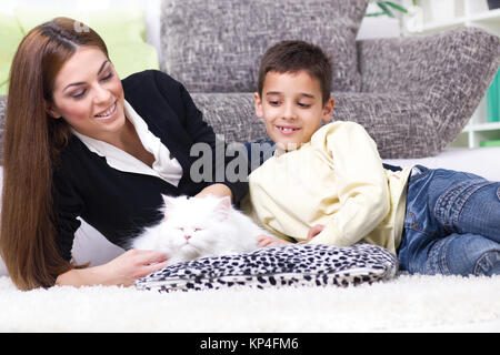 Mutter und Sohn auf dem Boden liegen und Streicheln weiße Perser Katze Stockfoto