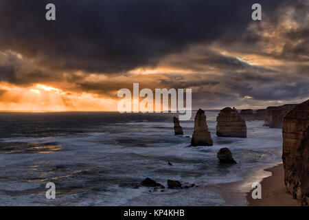 Stürmischen dunklen Wetter Sonnenuntergang über der berühmten Zwölf Apostel Kalksteinfelsen im Marina Park der Great Ocean Road in Victoria zur Einstellung orange Sun o Stockfoto