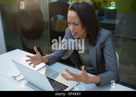 Gereizte Frau am Schreibtisch im Büro arbeiten Stockfoto