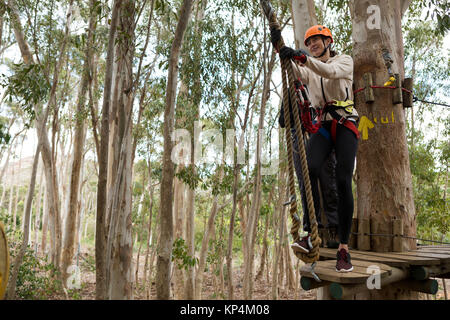 Frau tragen Schutzhelm fertig, auf Zip Line in den Wald zu klettern Stockfoto