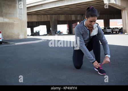 Weibliche Jogger ihr Schuh Schnürsenkel binden an einem sonnigen Tag Stockfoto