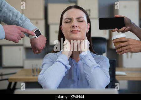 Kollege zeigt Zeit und Mobiltelefon zu frustrierten Frau im Büro Stockfoto
