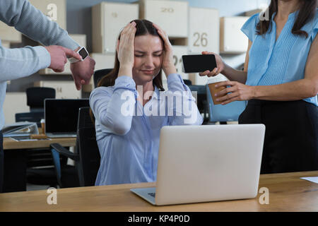 Kollege zeigt Zeit und Mobiltelefon zu frustrierten Frau im Büro Stockfoto