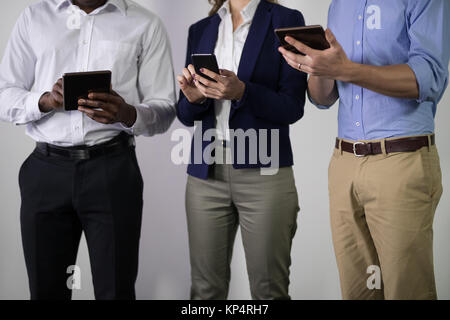 Den mittleren Abschnitt der männlichen und weiblichen Führungskräften mittels elektrischer Geräte im Büro Stockfoto