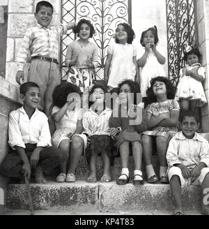 1950 s, Jordanien, historische Bild zeigt eine Gruppe von jordanischen Kindern auf Schritte vor einer Toreinfahrt zu lächeln und zu lachen Stockfoto