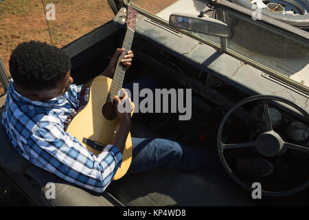 Mann spielt Gitarre im Auto an einem sonnigen Tag Stockfoto