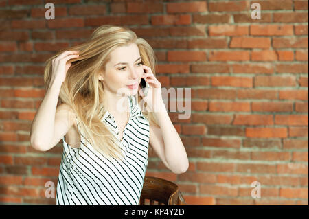 Ein blondes Mädchen ruft durch das Telefon gegen die Wand Hintergrund, Aufruf der Wohnung Reparatur Service. Werbung von Bauleistungen