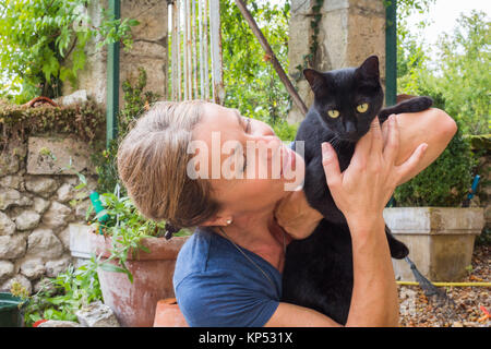 Frau mit einer schwarzen Katze auf dem Arm. Stockfoto