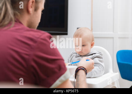 Vater seinen Sohn mit Babynahrung zu Hause füttern Stockfoto