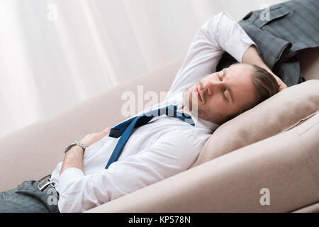 Müde, Geschäftsmann, schlafen auf einem Sofa in Hemd und Krawatte Stockfoto