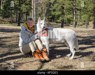 Frau mit einem weißen Hund in einem Wald Stockfoto