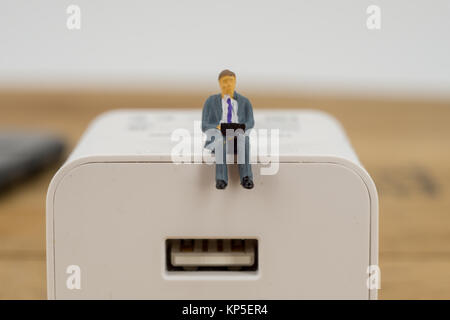Business, Technologie Konzept. Geschäftsmann Miniatur winzige Figur Spielzeug sitzen auf einem Netzstecker mit Kopie Raum Stockfoto