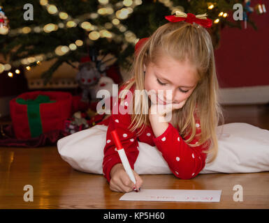 Adorable Schule Alter Mädchen schreiben Hinweis zu Santa auf Weihnachten zu verlassen Stockfoto